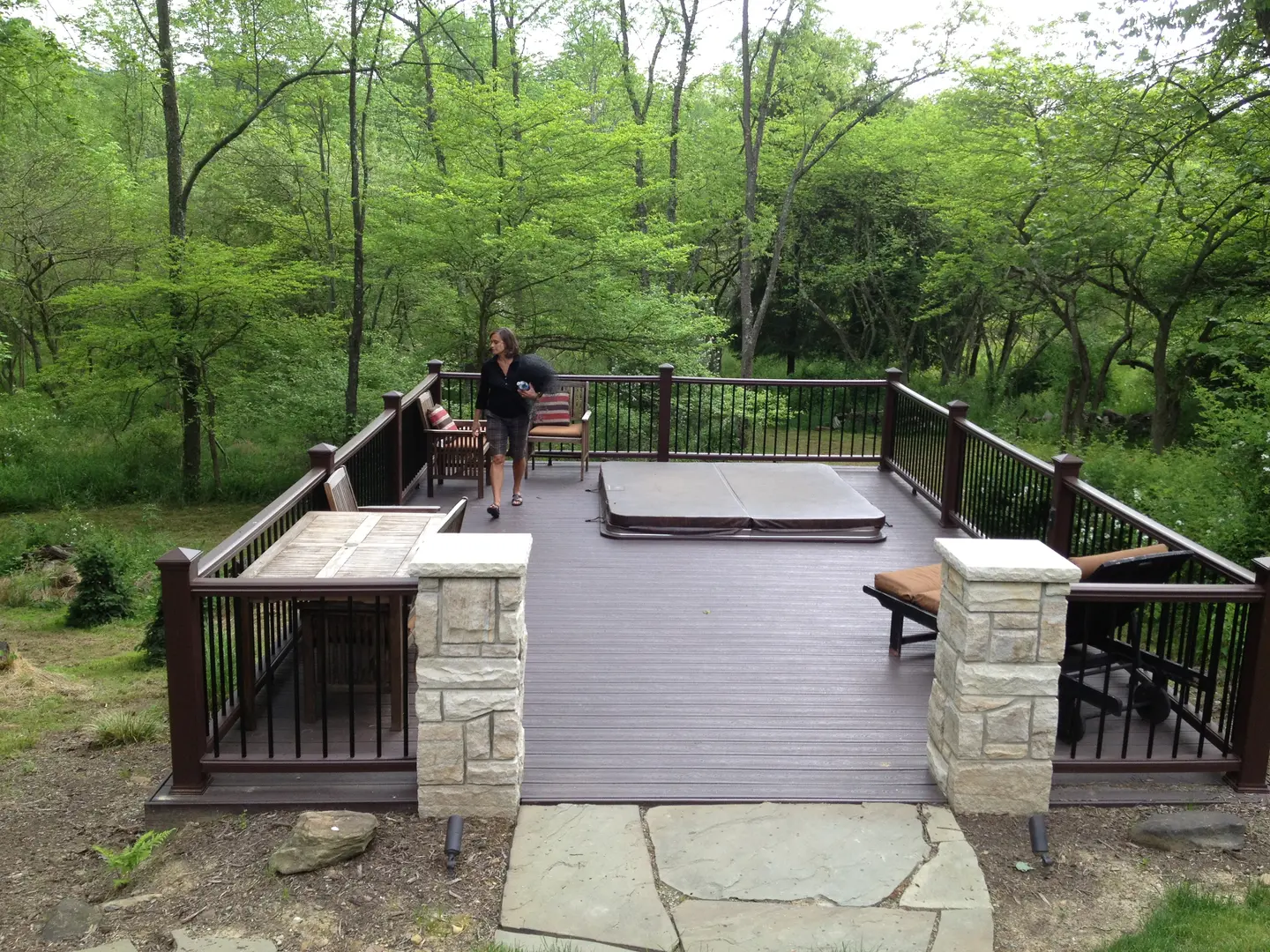 A man standing on top of a deck next to trees.