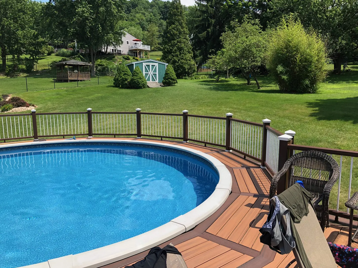 A pool with a wooden deck and a bench.