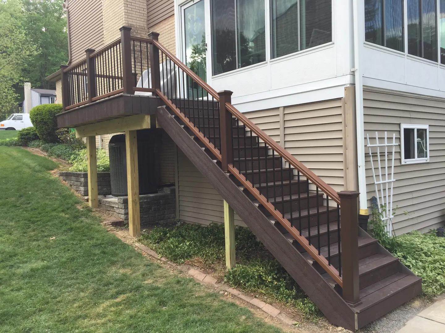 A brown staircase with black railing and white walls.