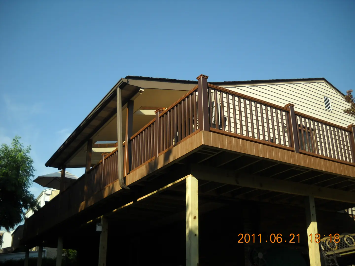 A large deck with wooden railing and a sky background