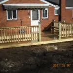 A wooden deck with a bench and railing.