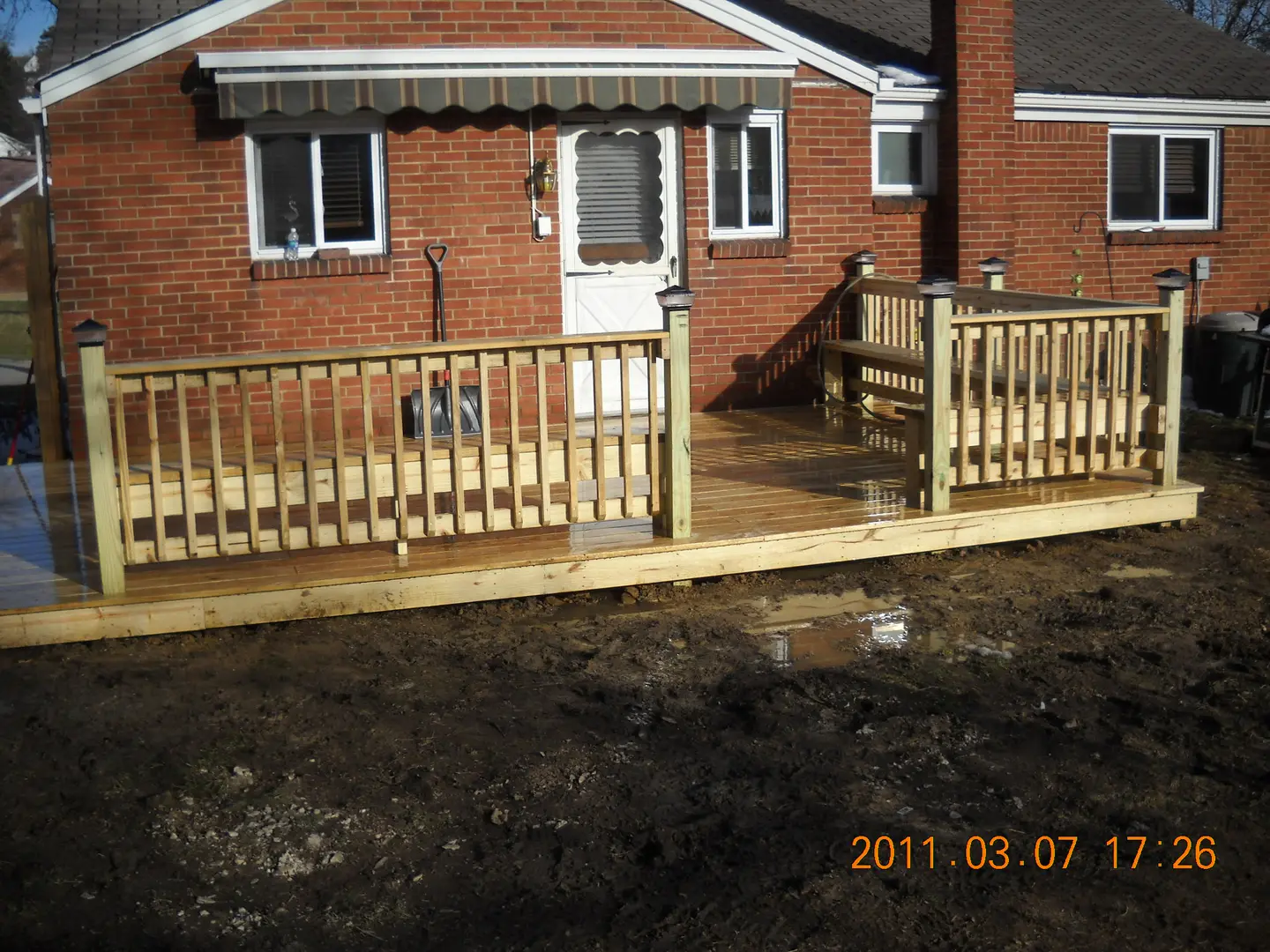 A wooden deck with a bench and railing.