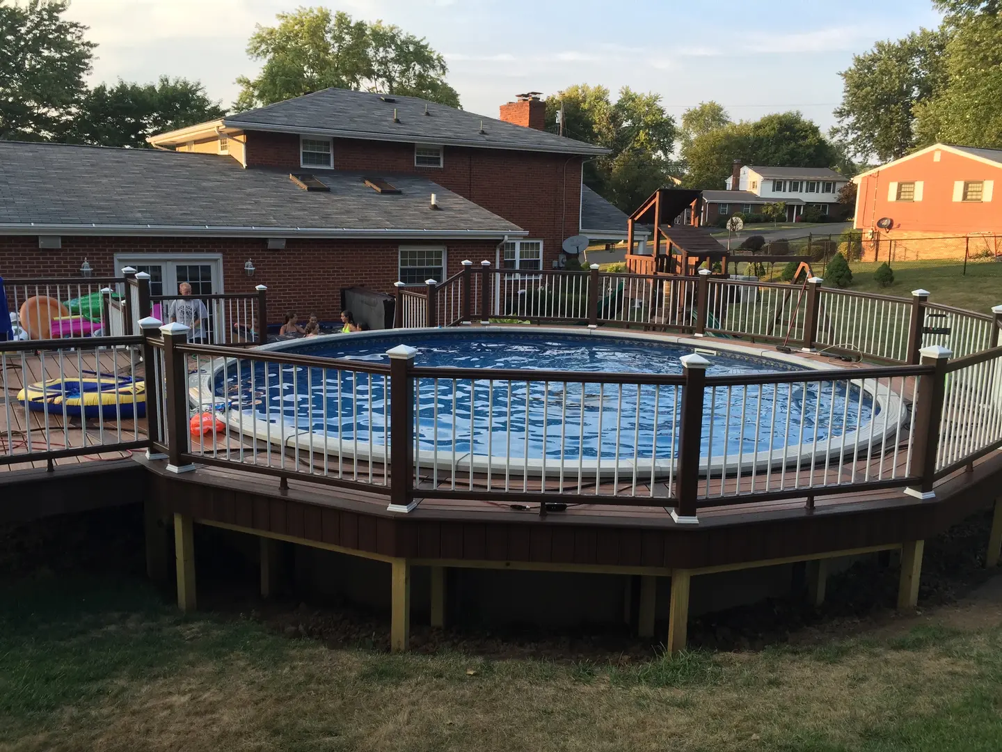 A pool with a wooden deck and a fence around it.