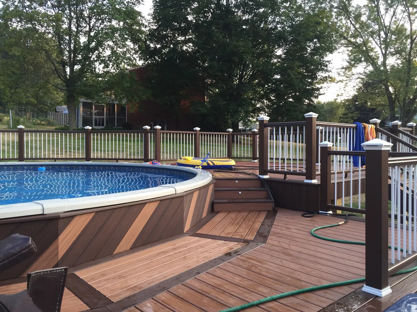 A pool with wooden deck and steps leading to the pool.