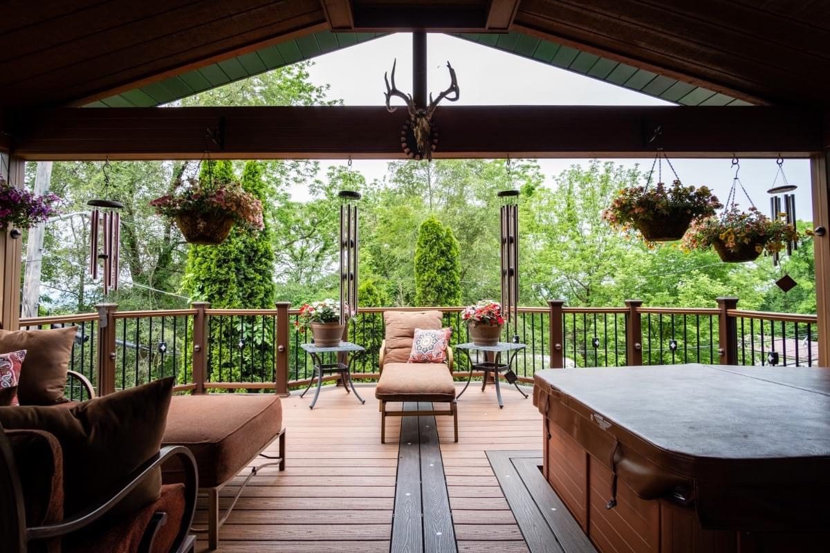 A patio with furniture and plants on the deck.