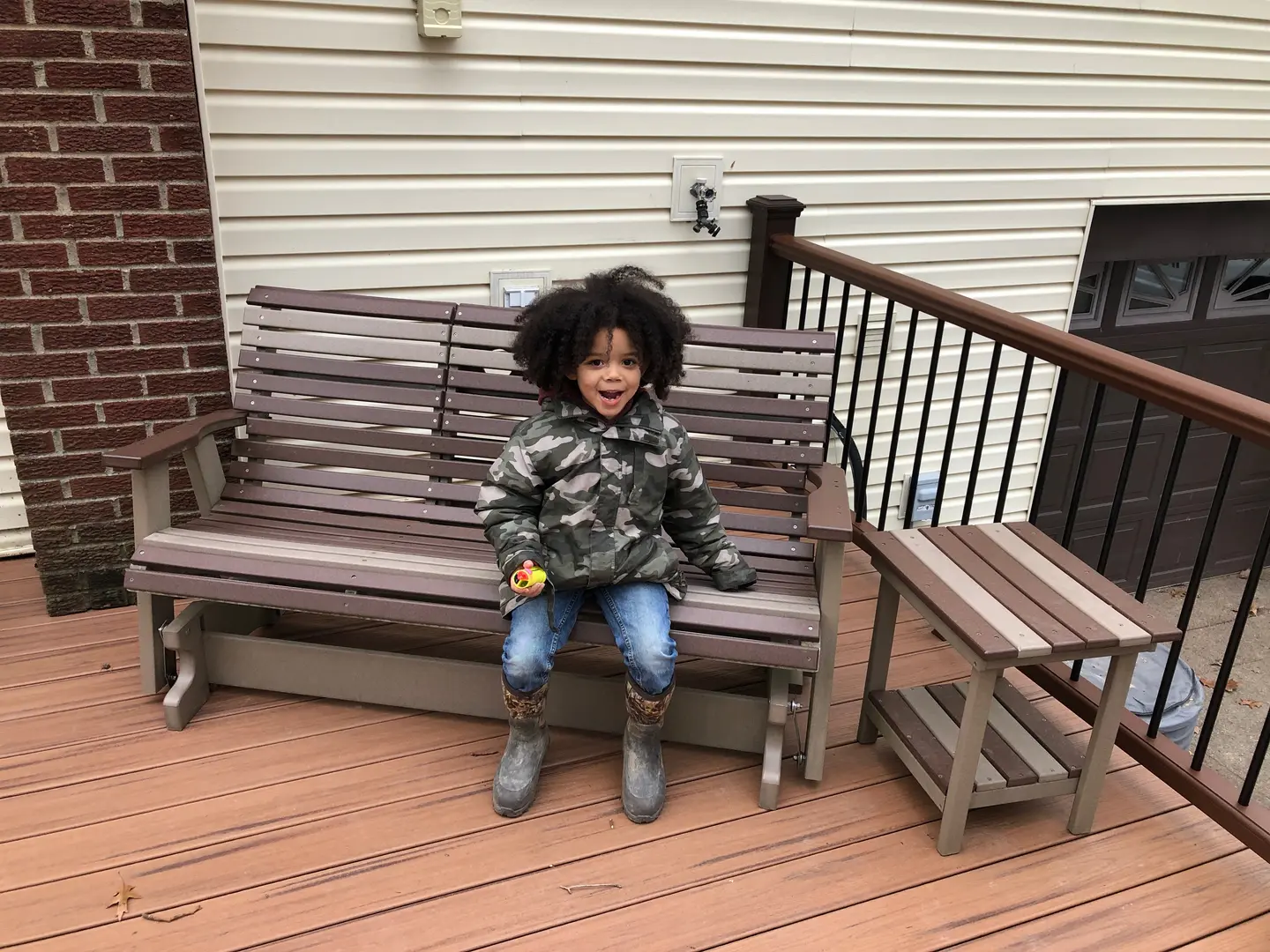 A young child sitting on top of a wooden bench.